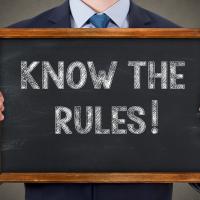 Picture of person holding sign that says Know the Rules