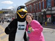 A runner poses for a picture with a person in a penguin costume.