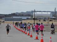 The front runner passes a group of runners on the opposite side of the road