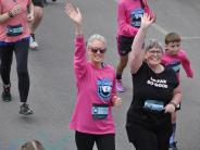 Two female runners are shown waving at the camera during the race