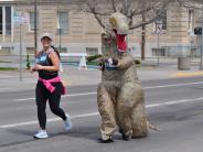 Two runners are shown, one of which is in a dinosaur costume