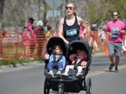 A runner is shown in the race pushing a stroller containing two children