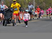 Several runners, including a small child, are running towards the finish line