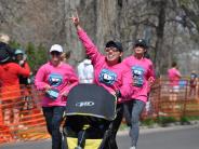 Many runners are shown shortly before reaching the finish line, including a mother celebrating as she pushes a stroller