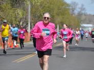 Many runners are shown in the stretch before reaching the finish line, including an older male runner