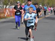 Many runners are shown in the stretch before reaching the finish line, including a young child