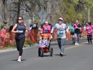 Many runners are shown in the stretch before reaching the finish line, including a mother pushing a stroller