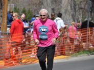 An older runner is shown making his way towards the finish line