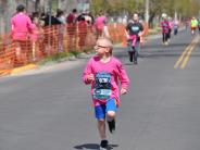A small child is shown running in the race, with runners behind her 