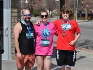 A group of three runners smiling after finishing the race and while wearing their medals