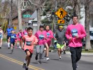 Many runners are shown running down the street, including several children