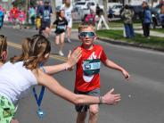 A young child receives high-fives as he runs in the race