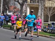 Several runners, including multiple children, running down the street 