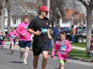 Many runners, including a father and son, are shown running down the street