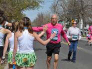 An older runner receives high-fives as he runs in the race