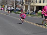 A young child runs down the street towards the finish line