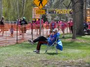 A gentleman sitting on the sidelines, watching the runners come to the finish line