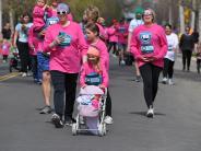 Several runners are shown walking to the finish line, including a little girl pushing a baby doll in a stroller