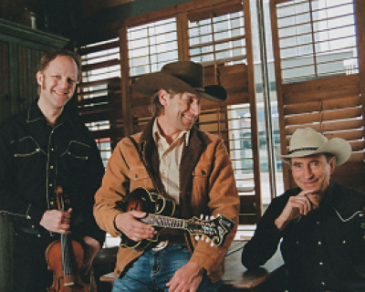 3 men in western wear. one holding a violin and another holding a guitar